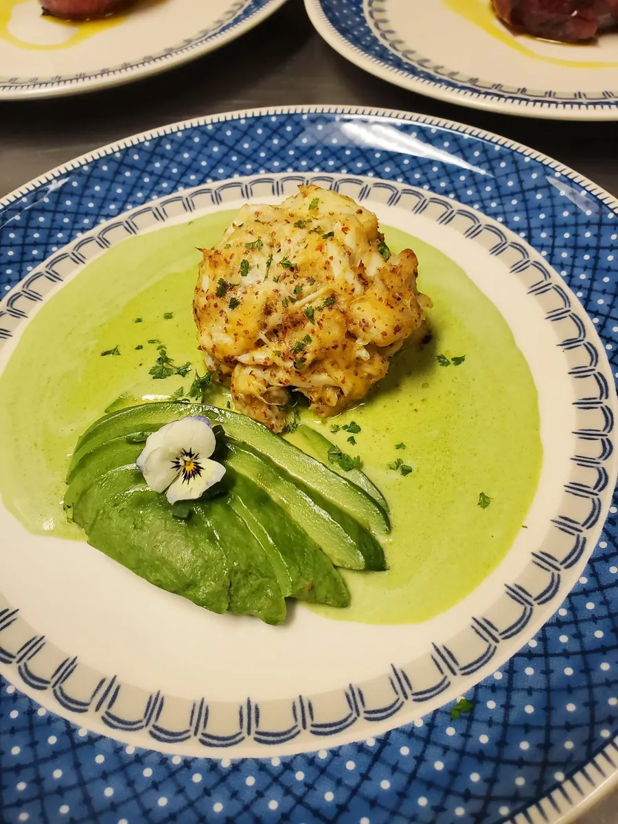 Seared fish with avocado and green sauce on a blue-rimmed plate