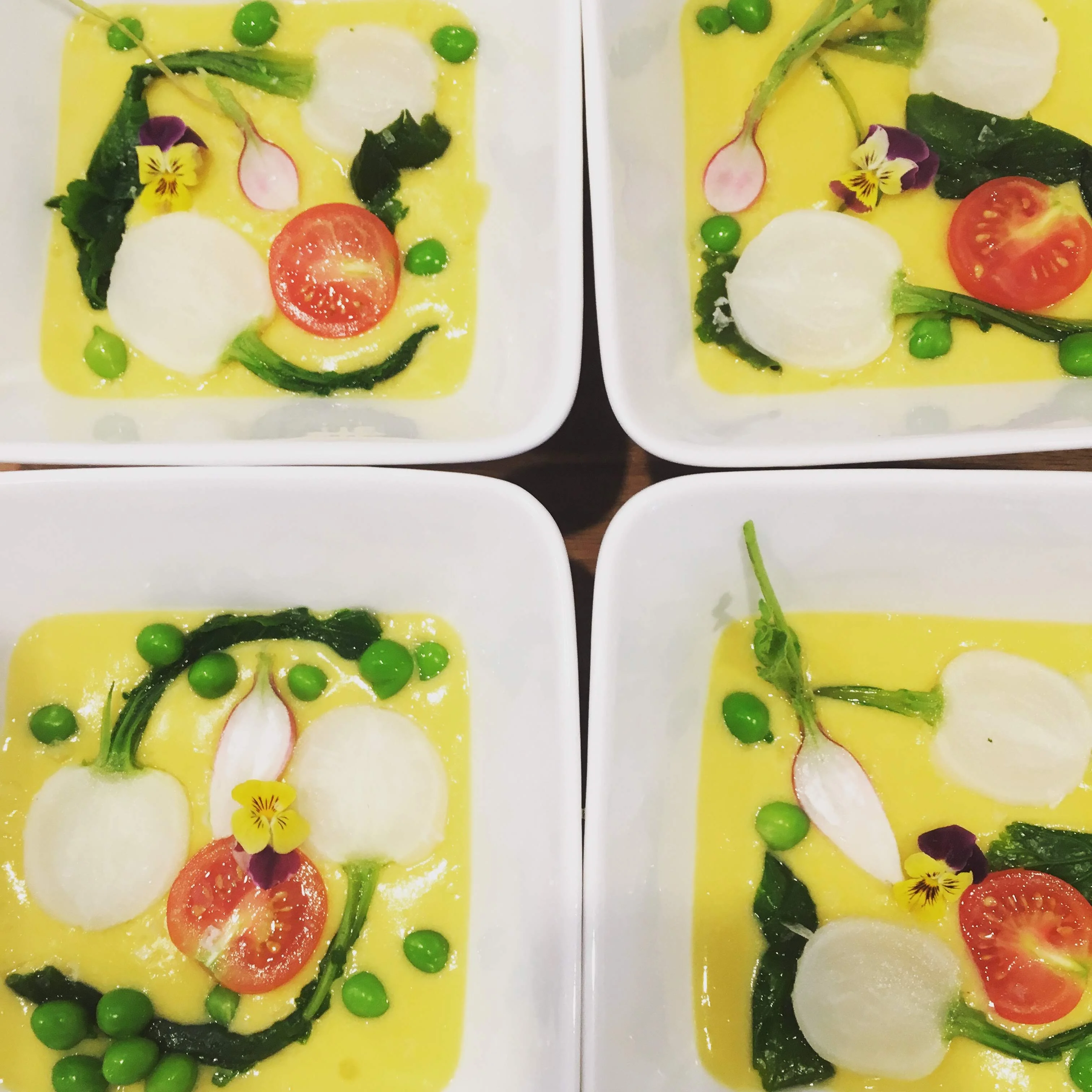 Chilled summer soup with cherry tomato, baby turnip, peas, and edible flowers at a Kauai private dinner
