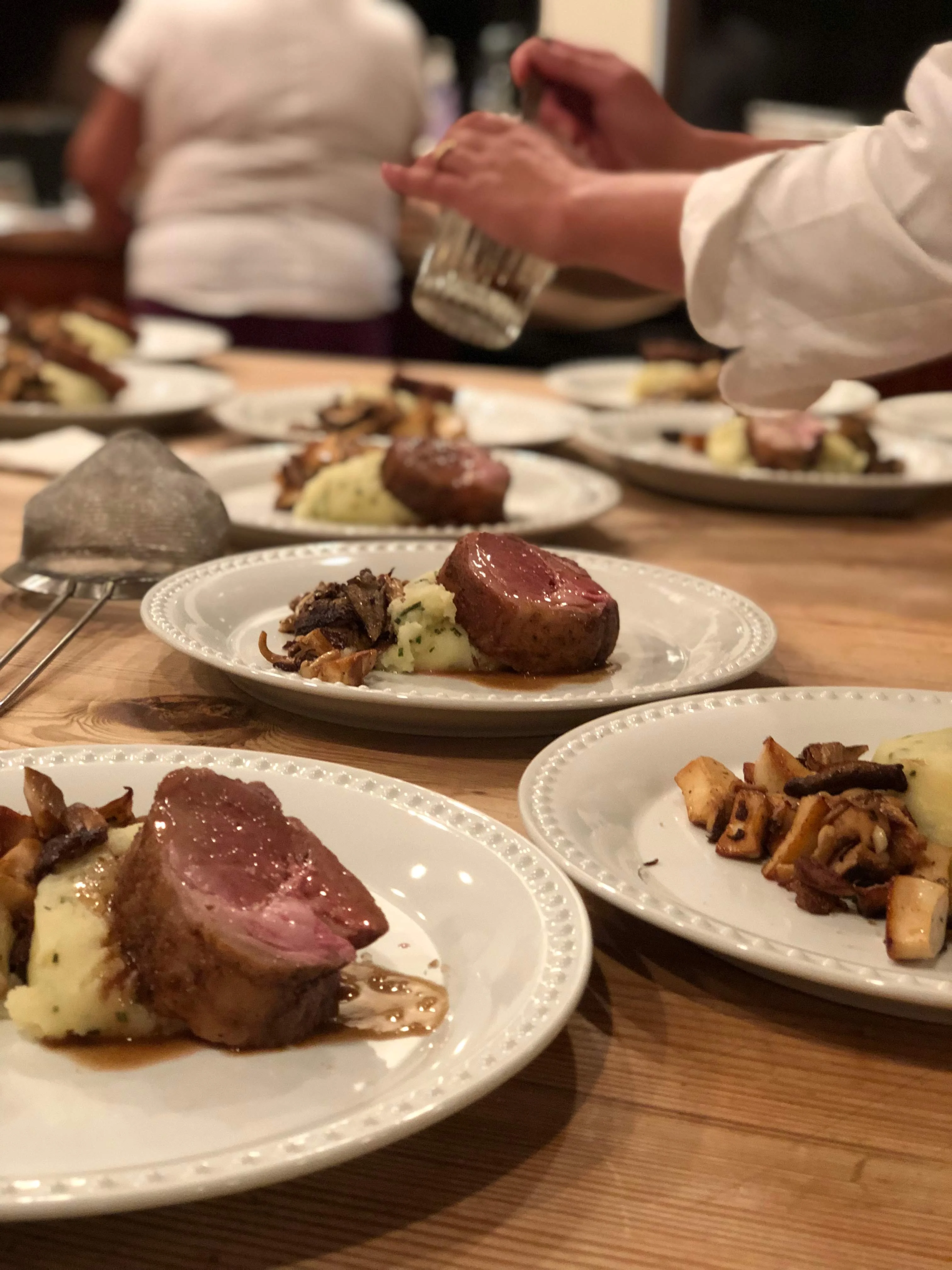 Chef plating beef tenderloin medallions with mashed potato and chanterelles at a Kauai private dinner